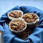 vegan pumpkin baked oatmeal cups in a basket lined with a blue napkin.
