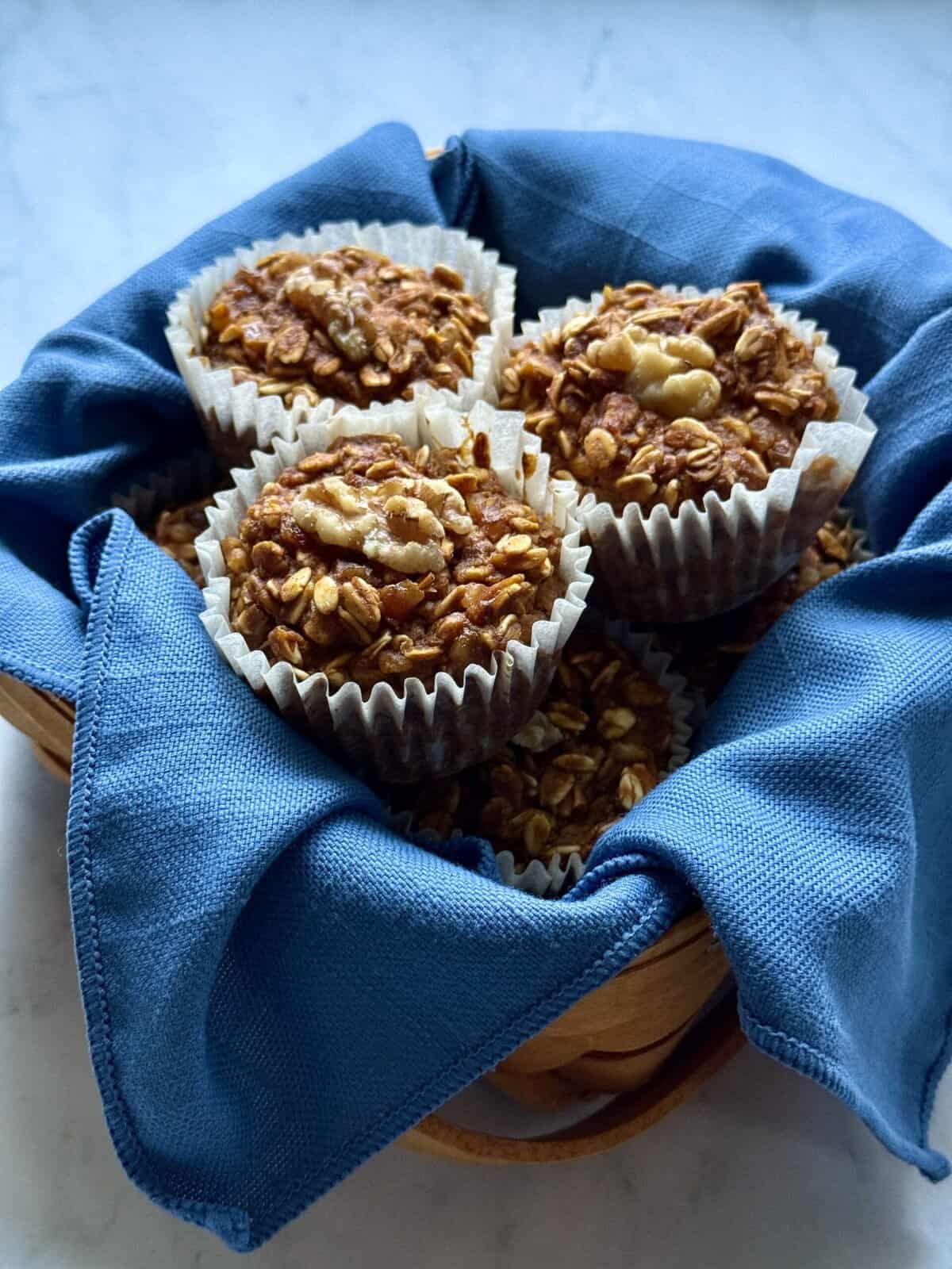 vegan pumpkin baked oatmeal cups in a basket lined with a blue napkin.