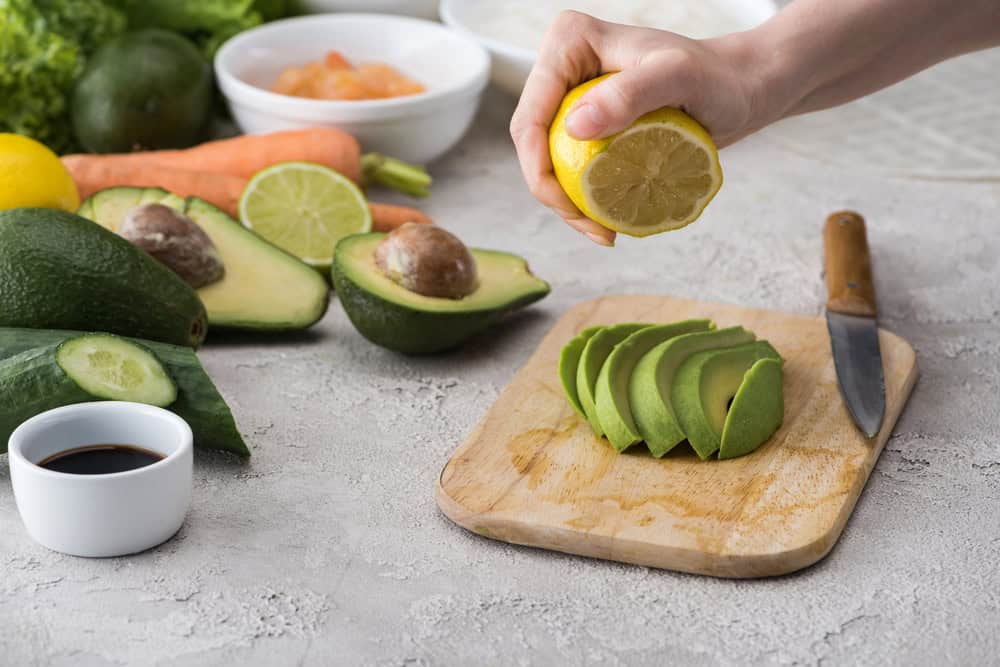 lemon being squeeze onto avocado slices