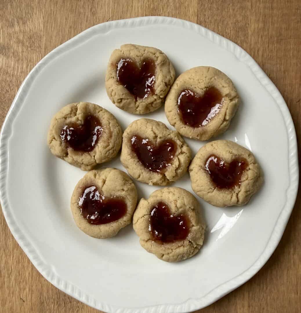 gluten-free thumbprint cookies on a plate with heart -shaped jam centers